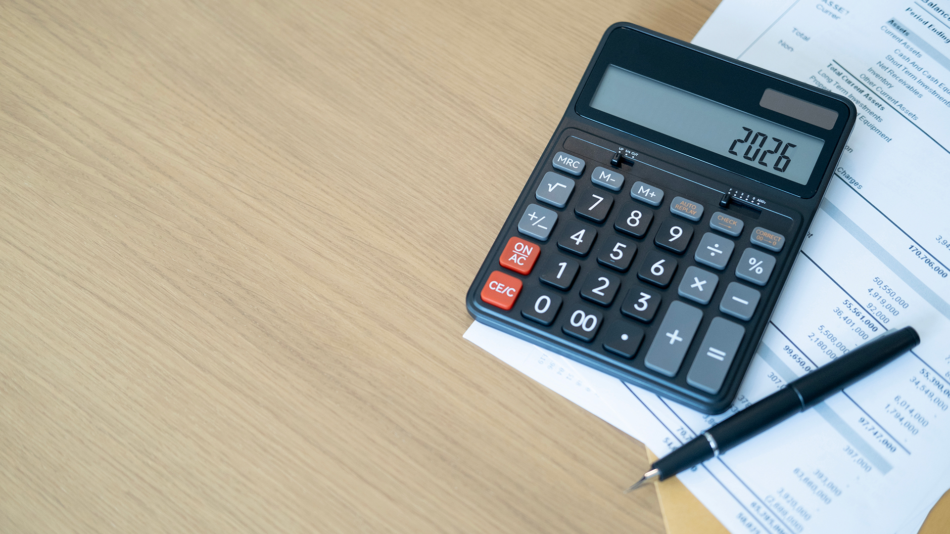 Calculator on the table with a pen and paper
