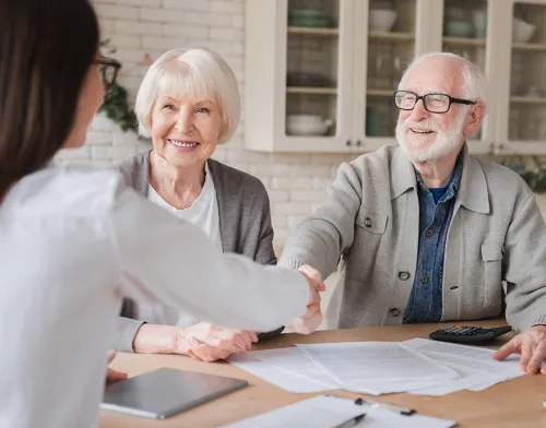 An elderly couple talking to a woman across a table