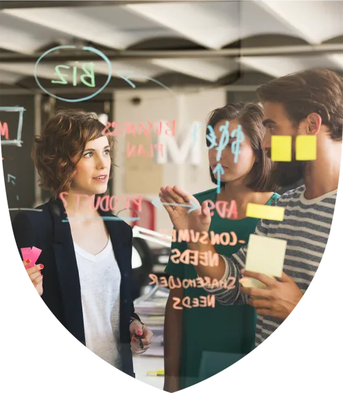 Three people working on a glass whiteboard