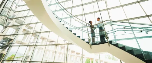 Two financial professionals speaking together on a staircase