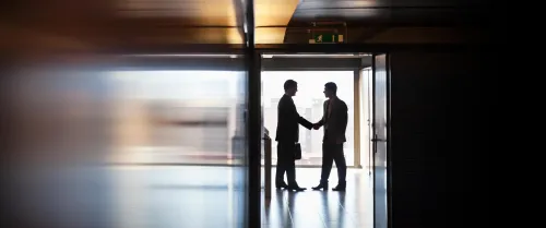Two people shaking hands down a hallway