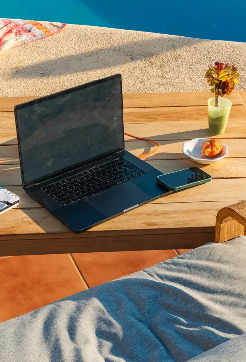A laptop sitting on a table by the pool