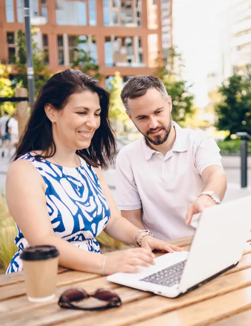 A man and woman smiling while looking at a computer together