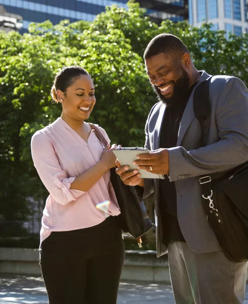 A man and woman smiling while looking at their notes together