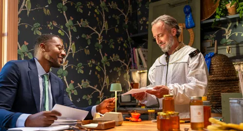 Man in beekeeper suit meeting with a financial advisor