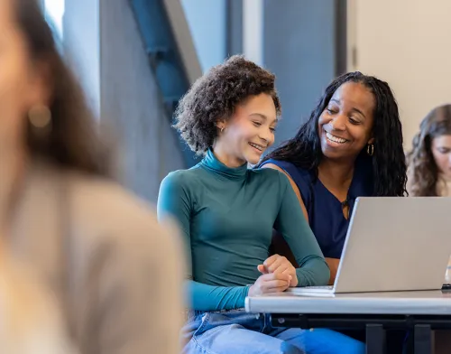 Female teacher helping a student at her desk