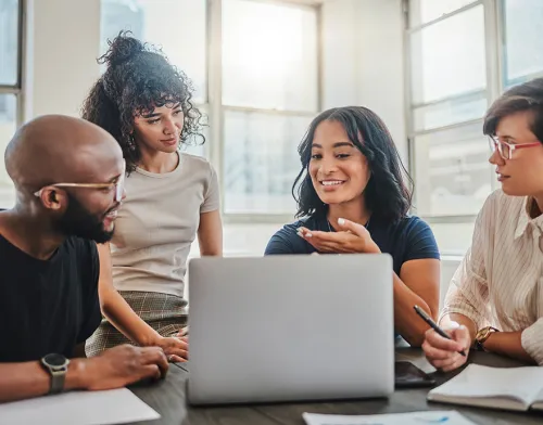 Group of friends sitting around a laptop and smiling