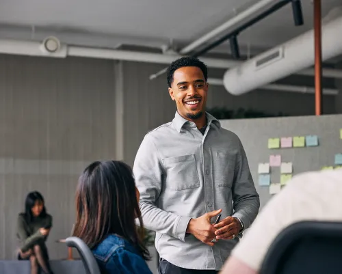 Man in his 30's smiling while talking to coworkers