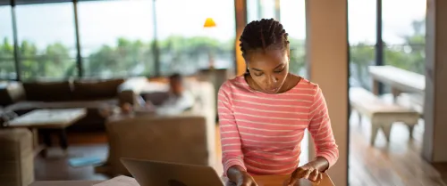 Woman standing in her kitchen on her laptop