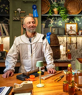Man in beekeeper suit standing at his desk
