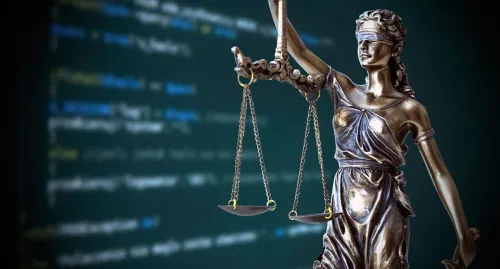 Statue of judge with scales in front of computer screen of code
